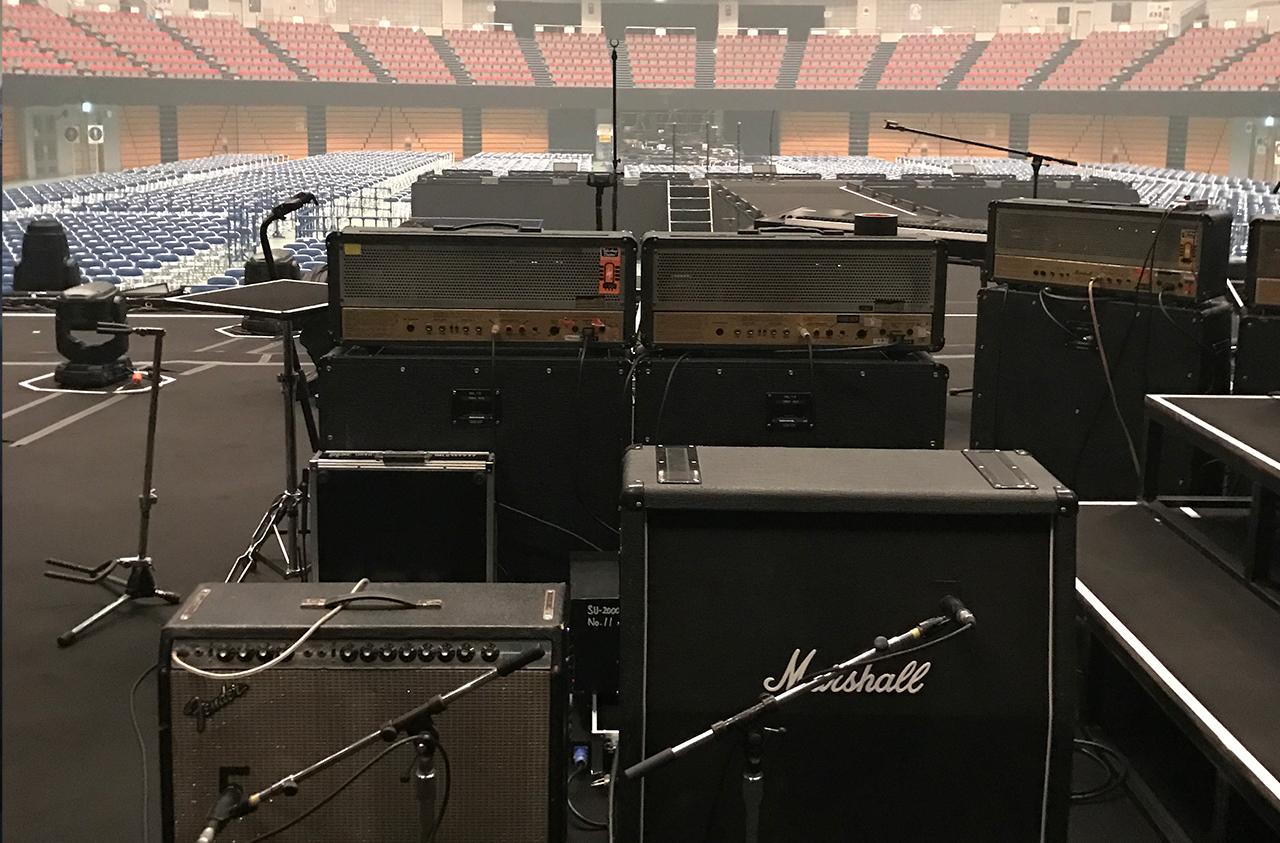 Backline equipment including amps, drums, and stage gear prepared for live performance use.