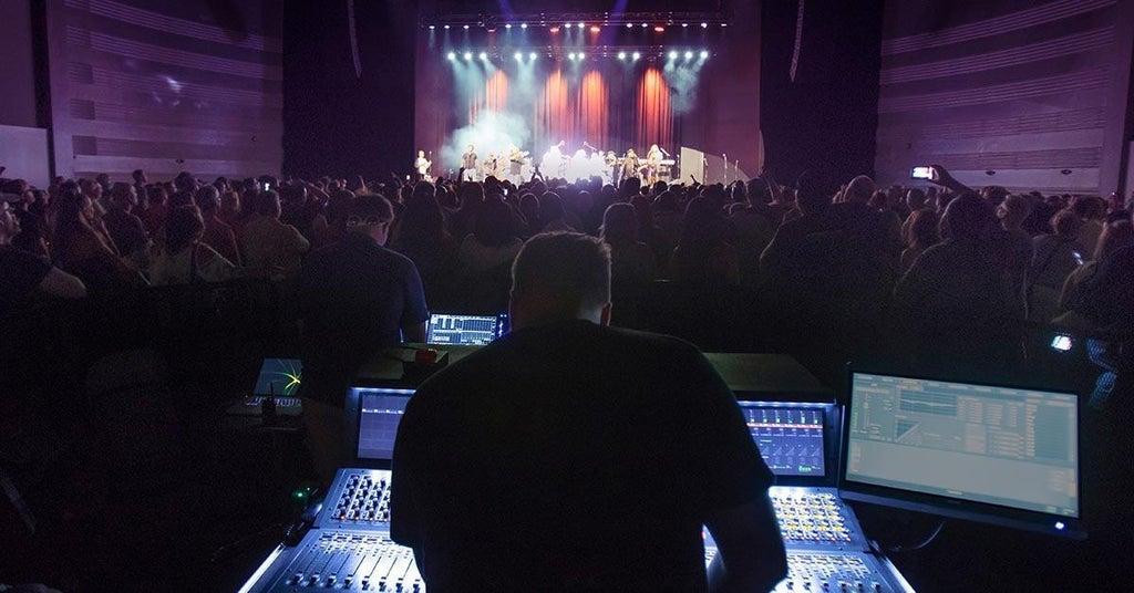 Mixing console and microphone-ready live audio control setup for event production.